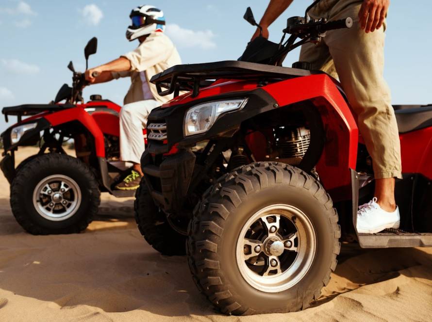 Off-road riders wearing safety gear navigate ATVs through a desert 
