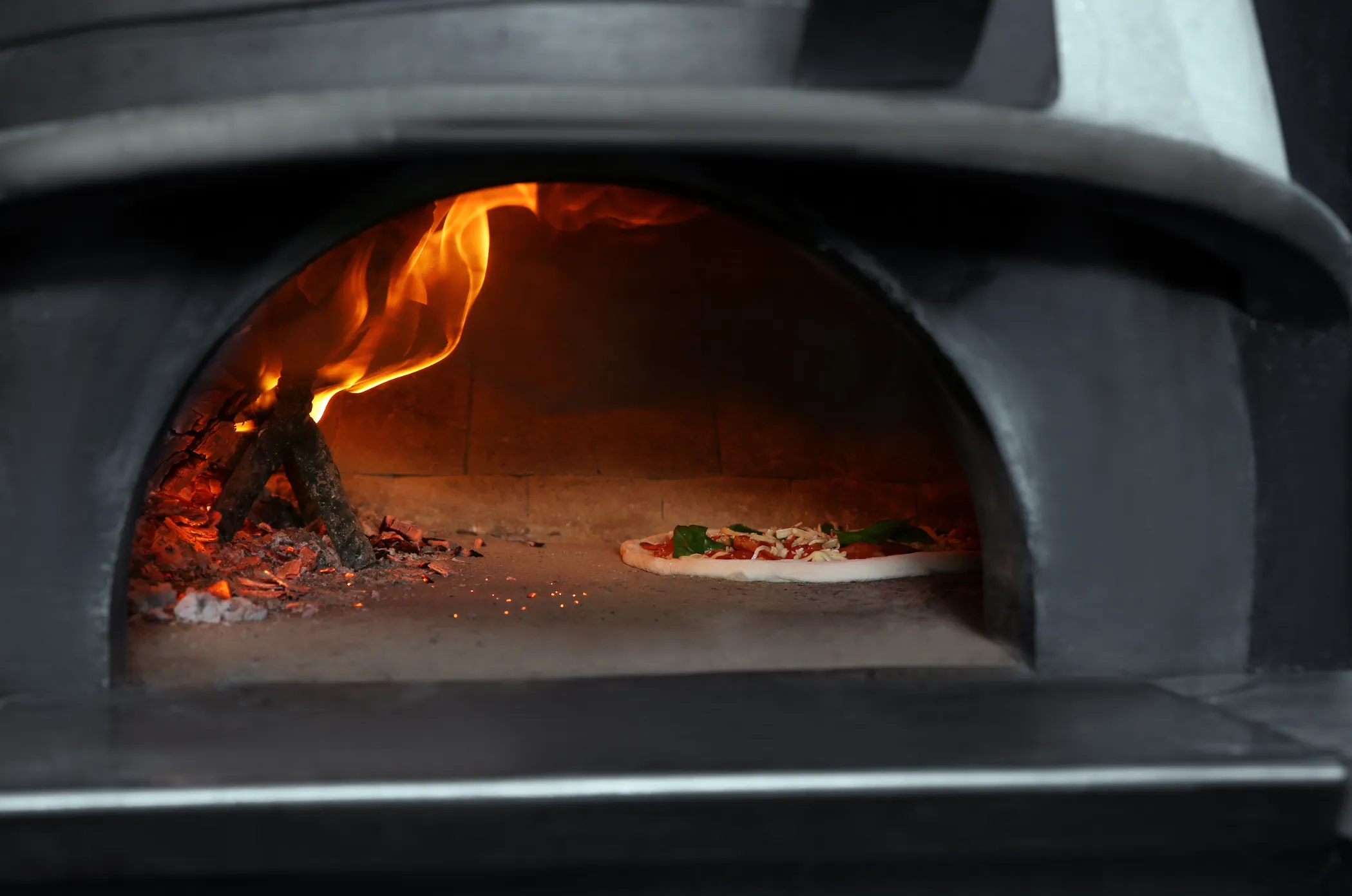 Pizza cooking inside a wood-fired pizza oven.