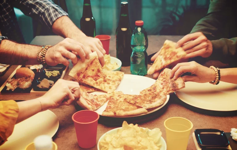 Pizza slices being shared by friends at a table.